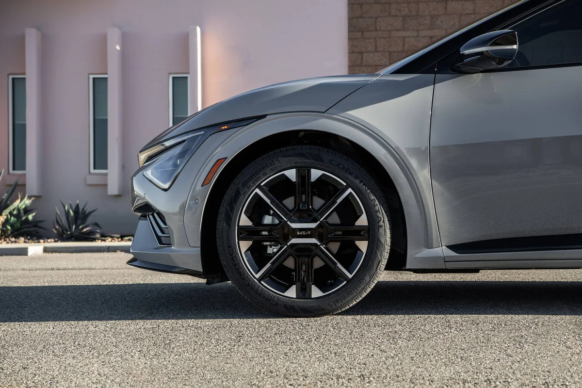 Silver 2026 Kia EV6 electric vehicle parked at modern charging station, angled front-side view showcasing sleek design and a…