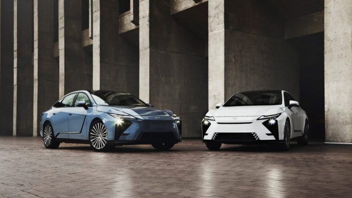 Blue and white 2026 Lexus ES 350h sedans parked front-facing in concrete garage with headlights on, showcasing hybrid sedan…