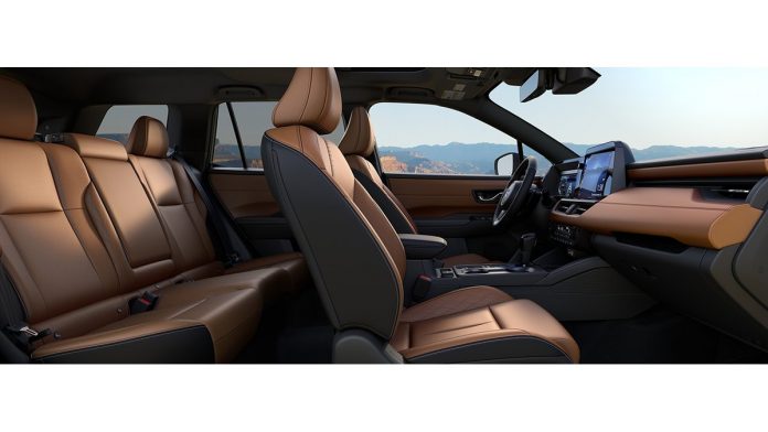2026 Subaru Outback interior featuring tan and black leather seats, steering wheel, and dashboard with mountains visible thr…