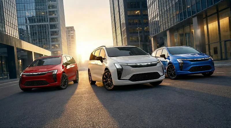 Three 2027 Chrysler Pacifica minivans in red, white, and blue parked on urban street at sunset between modern skyscrapers