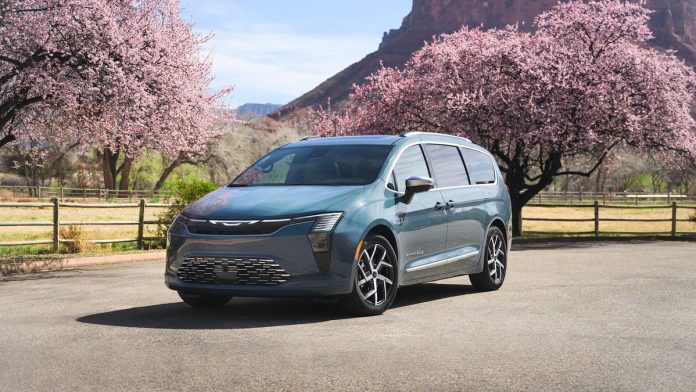 2027 Chrysler Pacifica minivan parked on rural road surrounded by blooming pink trees and mountains in background