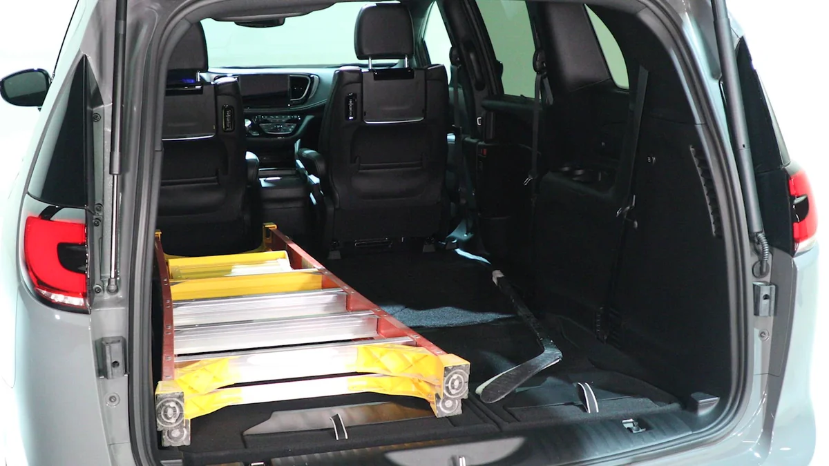 2027 Chrysler Pacifica rear cargo area with both doors open, showing yellow and silver extension ladders loaded inside the s…
