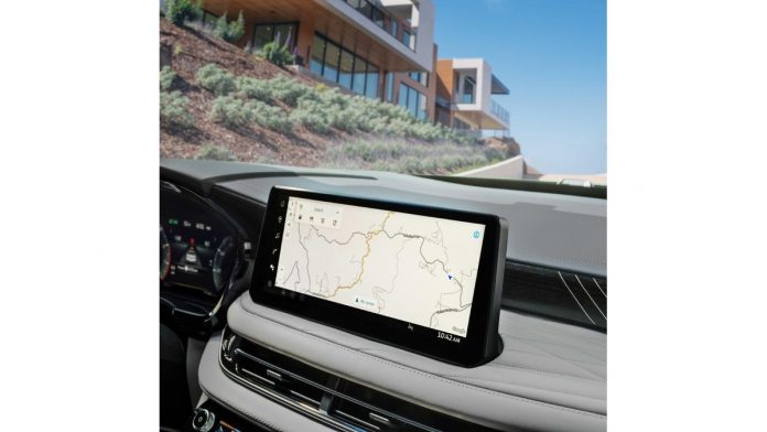 2027 Infiniti QX60 dashboard display showing navigation map, with desert landscape and modern architecture visible through w…