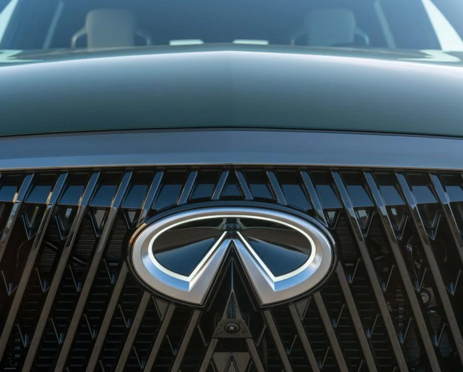 2027 Infiniti QX60 front grille featuring the luxury brand's signature Q emblem and vertical chrome slats against dark mesh…