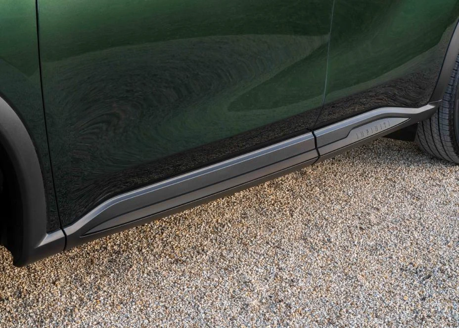 Green 2027 Infiniti QX60 side profile showing chrome trim and sculpted body panel detail on gravel surface