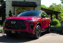 2027 Infiniti QX65 Starts at $53,990, Aims at BMW X3 After Years of Decline Red 2027 Infiniti QX65 luxury SUV parked in front of stone house with landscaped grounds, side three-quarter view showcasing…