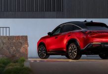 Infiniti Coats the QX65 in Real Gold, Invites You to Buy the Crossover Anyway 2027 Infiniti QX65 luxury crossover in vibrant red, photographed from the rear three-quarter angle against modern architectu…
