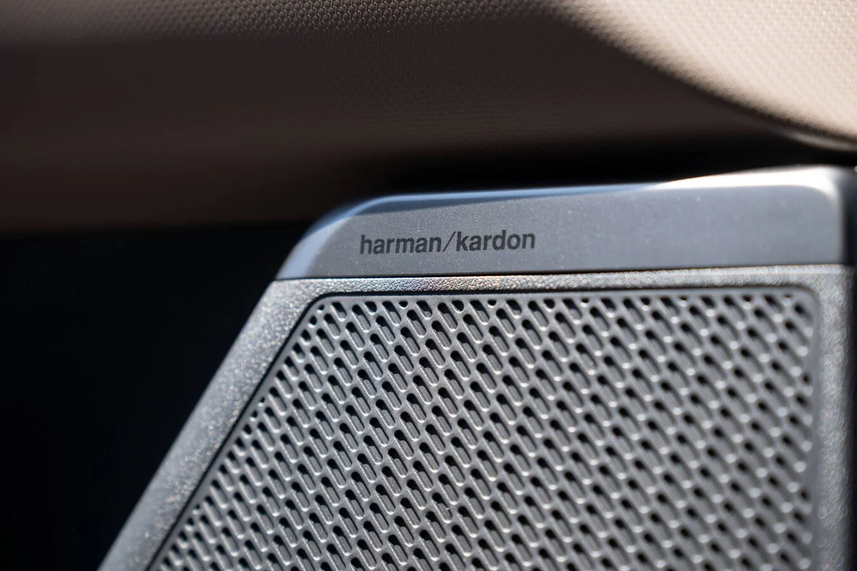 Harman Kardon premium speaker grille inside 2027 Kia Seltos, showing branded badge and perforated mesh audio component detai…