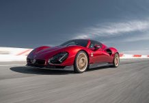 Alfa Romeo Hands Over First U.S. 33 Stradale, Displays Museum Example the Same Day Bright red Alfa Romeo 33 Stradale sports car driving on a racing circuit with white curbing and blue sky overhead.