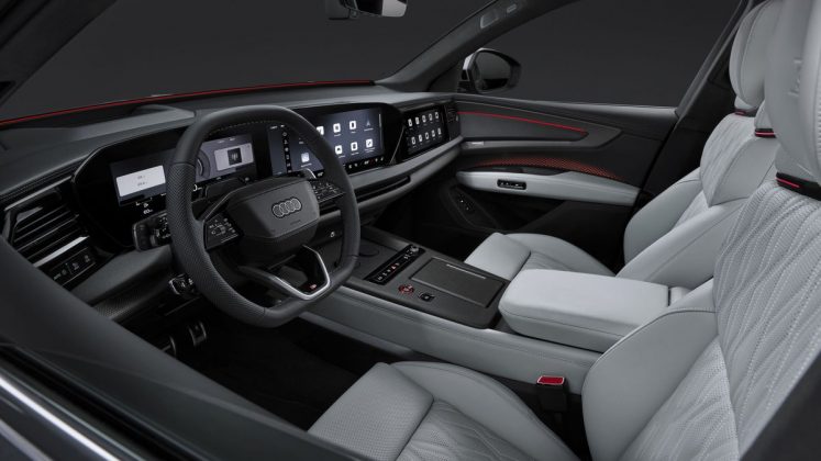 Audi Q9 interior featuring dual digital displays, leather steering wheel, light gray seats with red accent trim, and panoram&hellip;