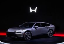 Honda Pivots to Hybrids With 15 Models by 2030 and a 30% Cost Cut Silver Honda hybrid SUV displayed on illuminated stage with glowing H logo above and red ambient lighting highlighting the v…
