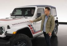Jeep Wrangler America250 Edition Arrives This Summer With Captain America Shield and $2,095 Upcharge Man in tan jacket gestures toward white 2026 Jeep Wrangler America250 Edition with red and blue side graphics and exposed ho…